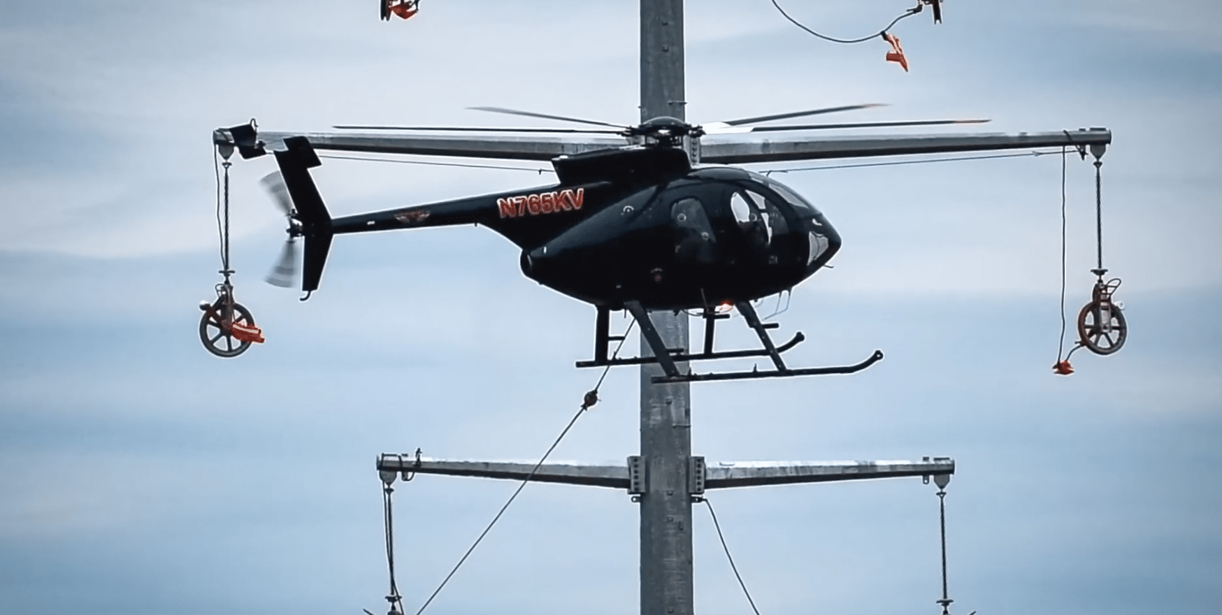 Helicopter Stringing Operation Using DDIN Helicopter Blocks Utility helicopter installing overhead power lines using DDIN helicopter blocks during a transmission line stringing operation